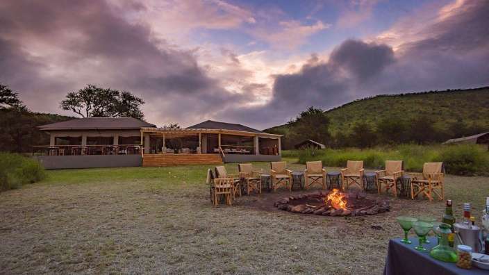 Eine Gruppe von Stühlen steht um ein Feuer in einem Feld