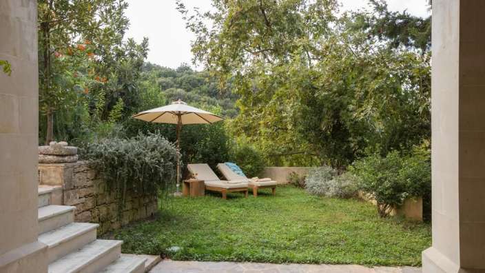 Ein Garten mit Liegestühlen und einem Sonnenschirm