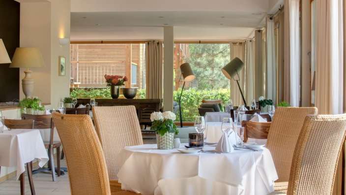 Ein Esszimmer mit einem Tisch und Stühlen mit weißen Tischdecken