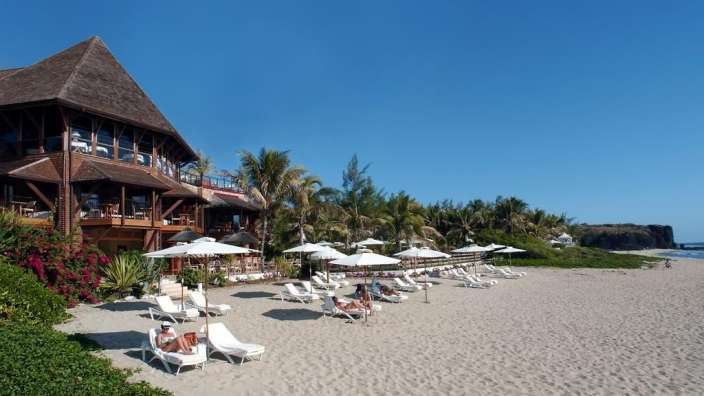 Ein Strand mit vielen Sonnenschirmen und Stühlen vor einem großen Gebäude