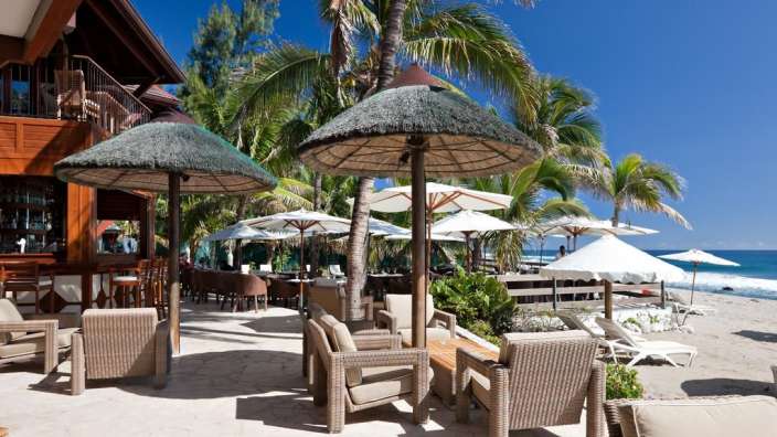Eine Terrasse mit Stühlen und Sonnenschirmen an einem Strand