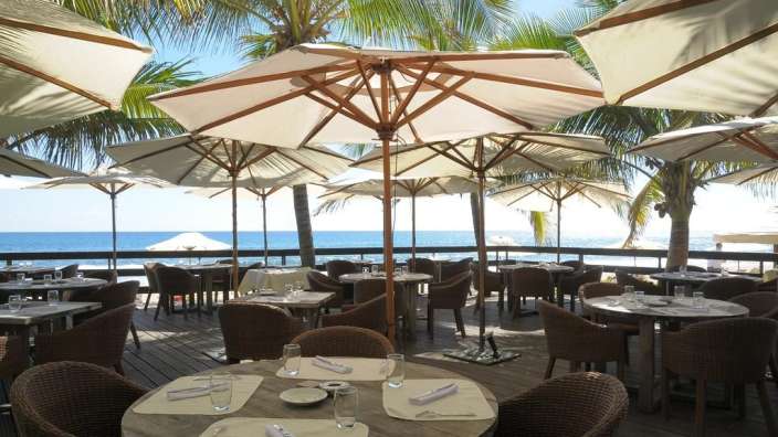 Eine Terrasse mit Tisch und Stühlen und Regenschirmen mit Blick auf den Ozean