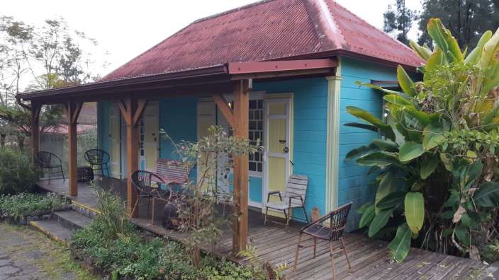 Ein blaues Haus mit einem roten Dach und einer Veranda