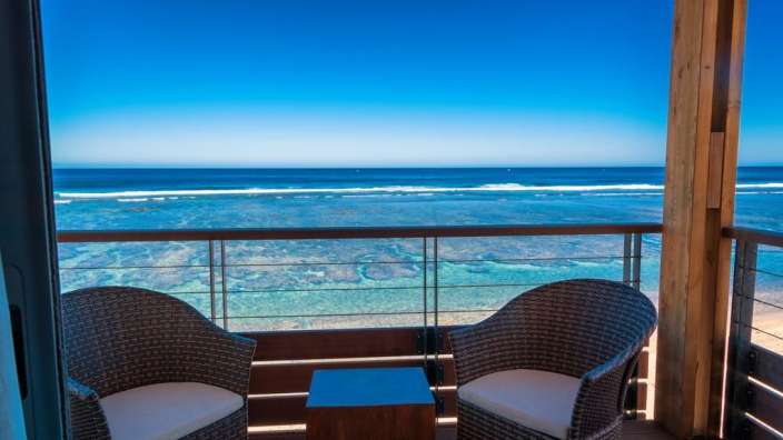 Zwei Stühle und ein Tisch auf einem Balkon mit Blick auf das Meer