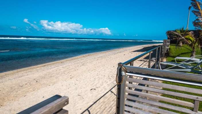 Ein Holzsteg führt zu einem weißen Sandstrand