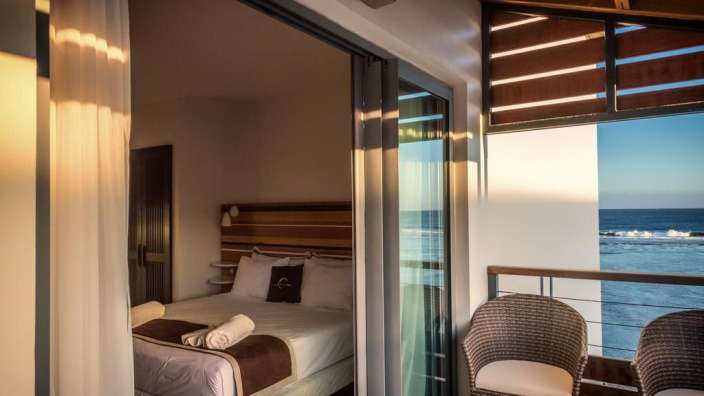 Ein Hotelzimmer mit einem Bett und zwei Stühlen mit Blick auf das Meer