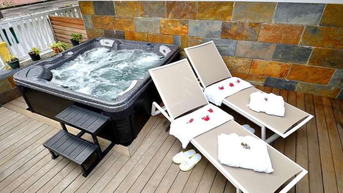 Zwei Liegestühle neben einem Whirlpool auf einem Deck