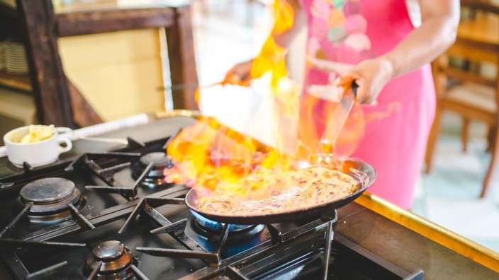Eine Frau in einer rosa Schürze kocht auf einem Herd