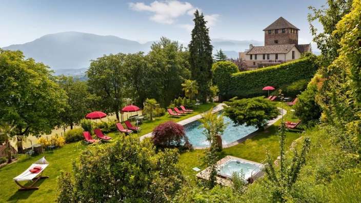 Ein Garten mit einem großen Pool und roten Sonnenschirmen