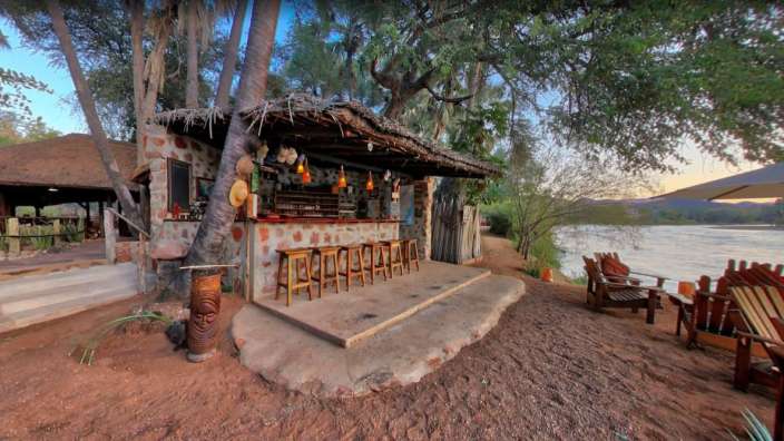 Eine kleine Bar mit Stühlen und einem Totem davor