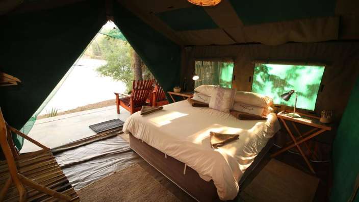 Ein Bett in einem Zelt mit Blick auf einen See