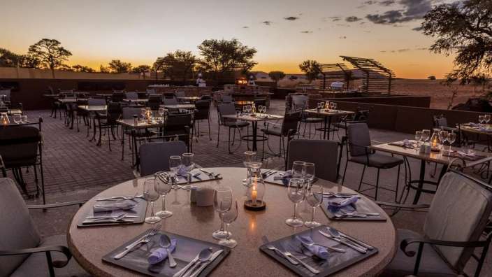Ein Tisch mit Tellern und Gläsern auf einer Terrasse bei Sonnenuntergang