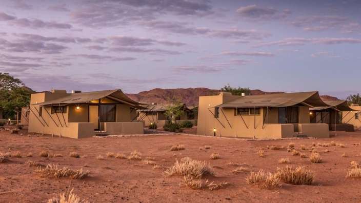 Eine Gruppe von Zelten in der Wüste mit Bergen im Hintergrund