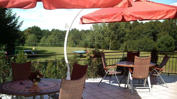 Ein Tisch und Stühle auf einem Balkon mit einem roten Regenschirm