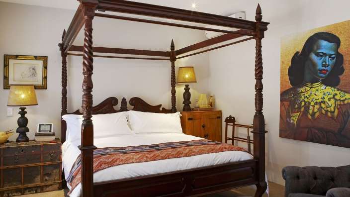 Ein Schlafzimmer mit einem Himmelbett und einem Gemälde an der Wand