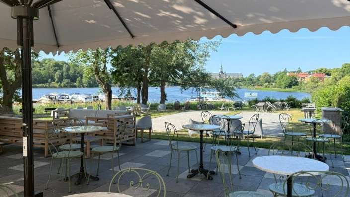 Tische und Stühle auf einer Terrasse mit Blick auf einen See