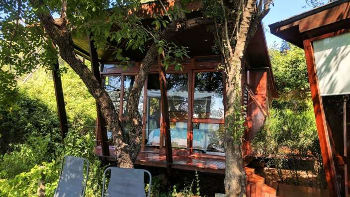 Ein Baumhaus mit vielen Fenstern und einem Bett darauf