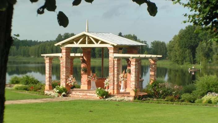 Ein Ziegelpavillon mit einem Metalldach steht in der Nähe eines Sees
