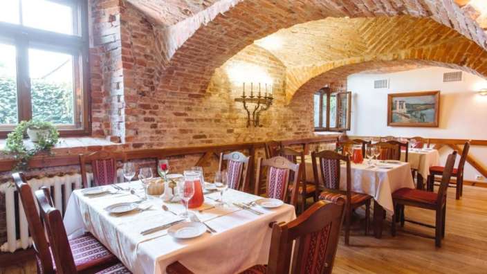 Ein Speisesaal mit Tischen und Stühlen und einem Gemälde an der Wand