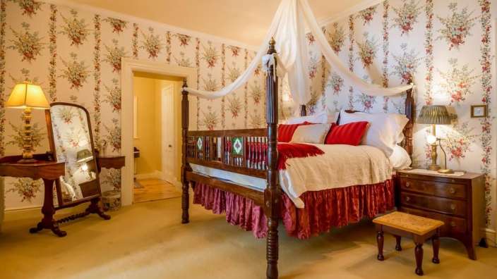 Ein Schlafzimmer mit einem Himmelbett und Blumentapeten
