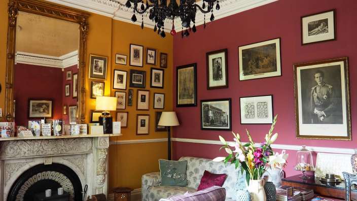 Ein Wohnzimmer mit rosa Wänden und einem schwarzen Kronleuchter