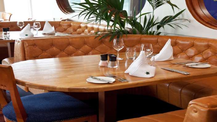 Ein Restaurant mit braunen Ledersofas und einem Holztisch