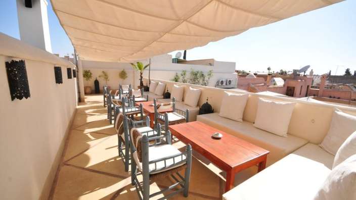 Eine Terrasse mit weißen Möbeln und einem roten Tisch