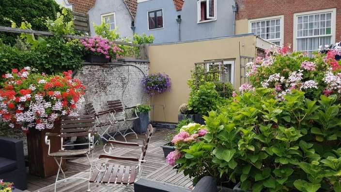 Eine Terrasse mit Stühlen und einem Tisch mit Blumen darauf