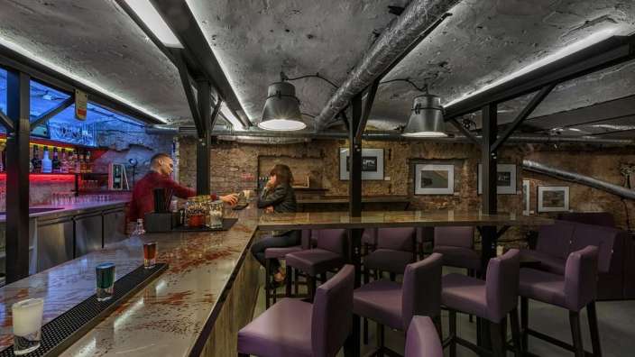 Eine Frau sitzt an einer Bar und trinkt einen Drink