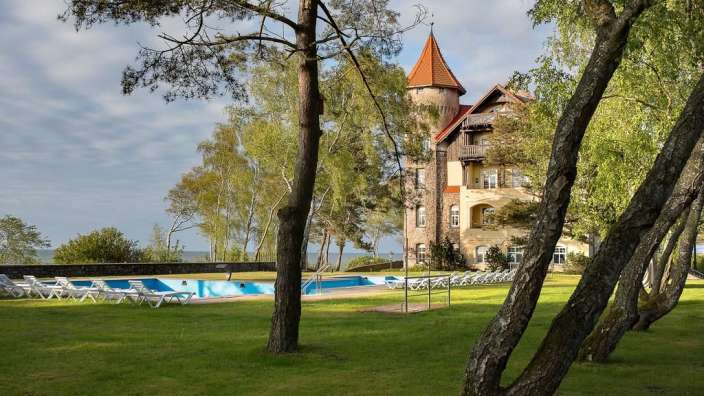 Ein großes Gebäude mit einem roten Dach und einem Pool im Vordergrund