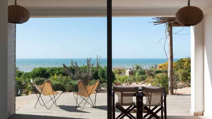 Ein Tisch und Stühle auf einer Terrasse mit Blick auf das Meer