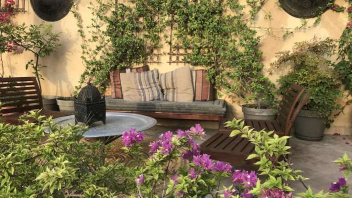 Ein Wohnzimmer mit einer Bank und Stühlen und lila Blumen