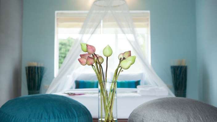 Ein Schlafzimmer mit einem Bett und einer Vase mit Blumen darauf