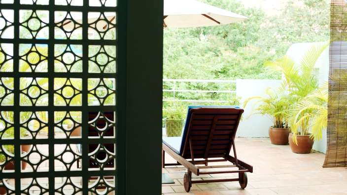 Ein Liegestuhl sitzt auf einem Balkon neben einem Sonnenschirm