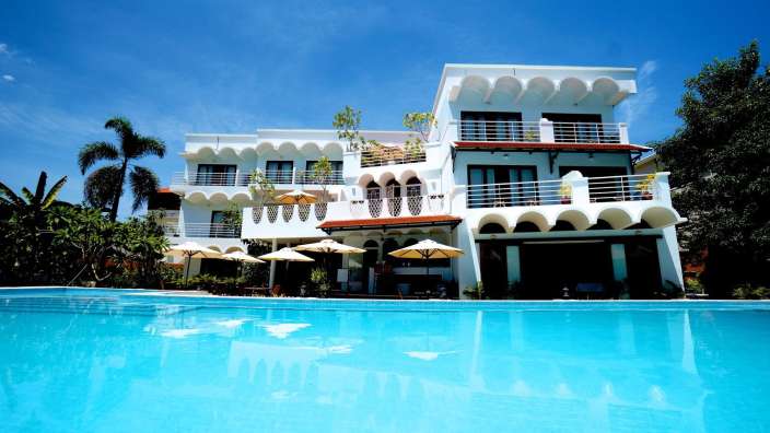 Ein großes weißes Gebäude mit einem Pool davor