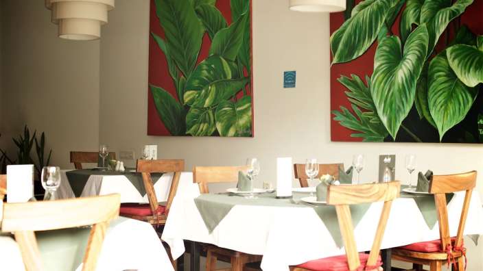 Tische und Stühle in einem Restaurant mit Gemälden an der Wand