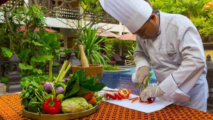Ein Koch schneidet Gemüse auf einem Schneidebrett