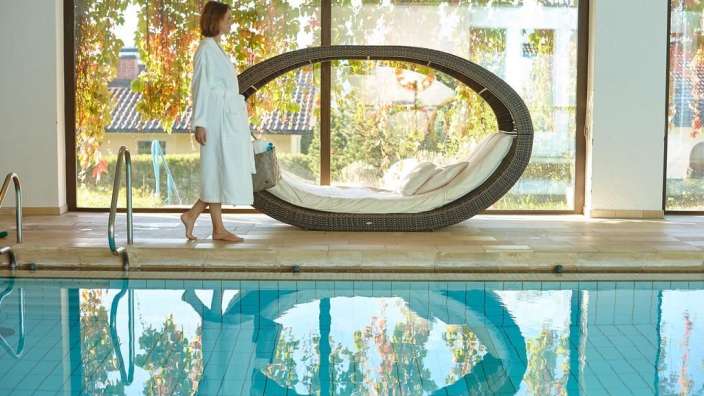 Eine Frau in einem Bademantel geht neben einem Swimmingpool