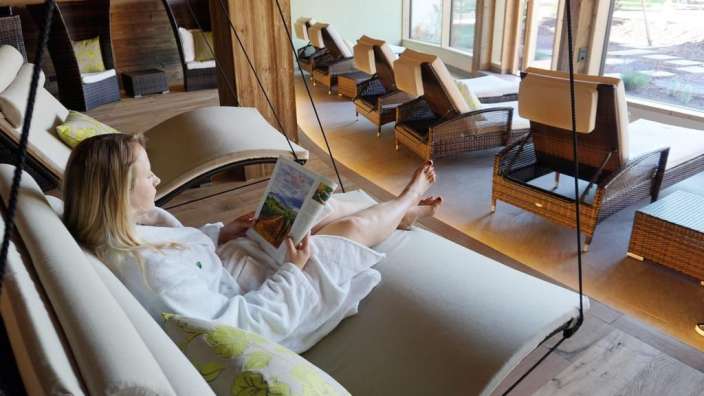 Eine Frau sitzt auf einer Schaukel und liest ein Buch