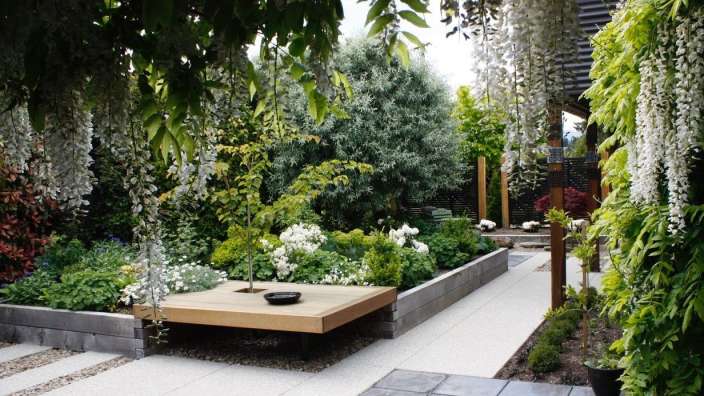 Ein Garten mit weißen Blumen und einem Holztisch