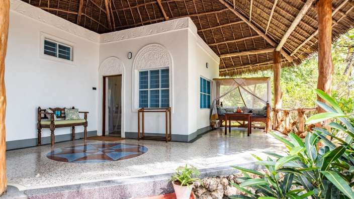 Ein weißes Haus mit einem Strohdach und einem Tisch