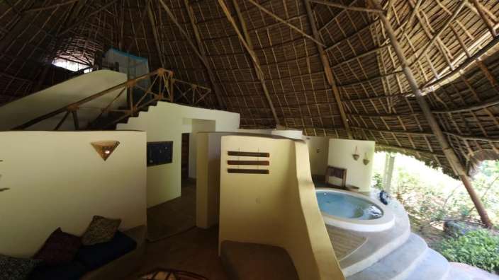 Ein Haus mit Strohdach und einem Whirlpool in der Mitte