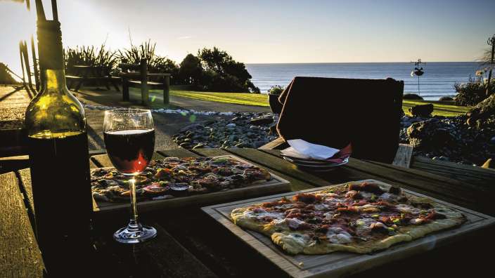 Ein Tisch mit zwei Pizzas und einem Glas Wein