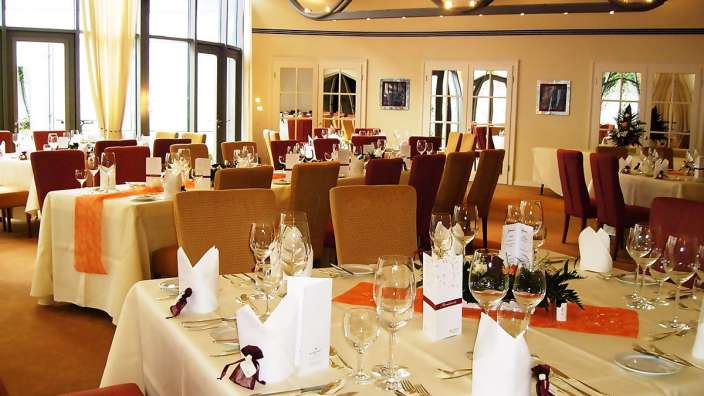 Ein Speisesaal mit Tischen und Stühlen und Gläsern