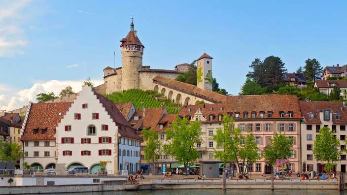 Eine Reihe von Gebäuden neben einem Fluss mit einem Turm darauf