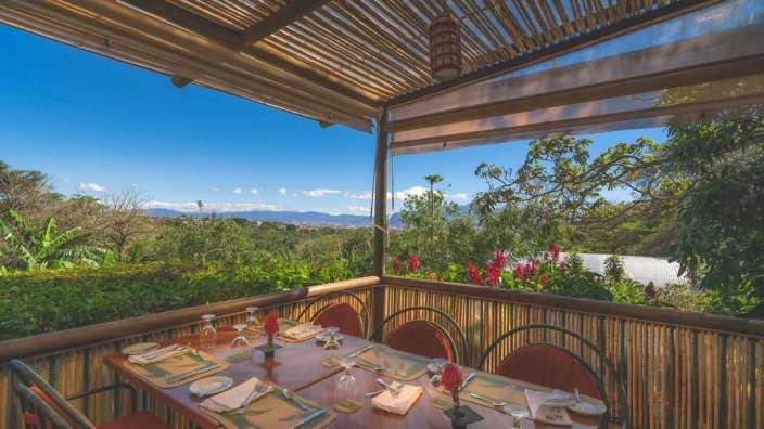 Ein Tisch und Stühle auf einer Terrasse mit Blick auf die Berge