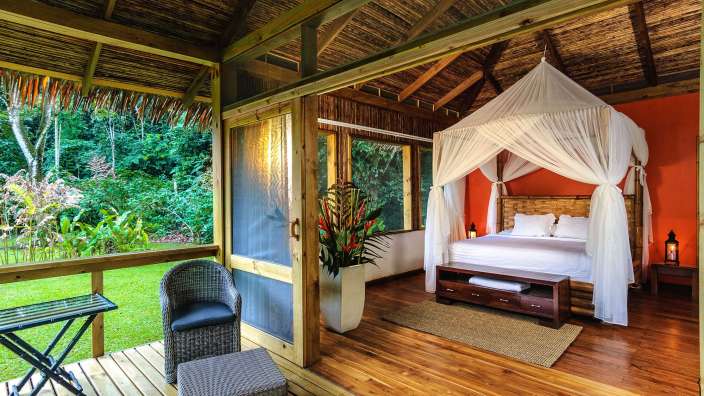 Ein Zimmer mit einem Himmelbett und einem Stuhl