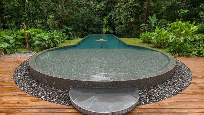 Eine Person schwimmt in einem großen Pool im Dschungel