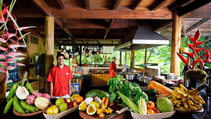 Ein Koch steht in einer Küche voller Obst und Gemüse