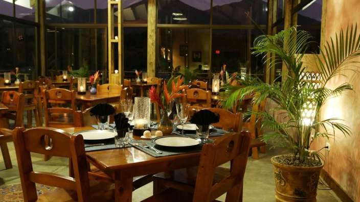 Ein Esszimmer mit Tischen und Stühlen und einer Palme